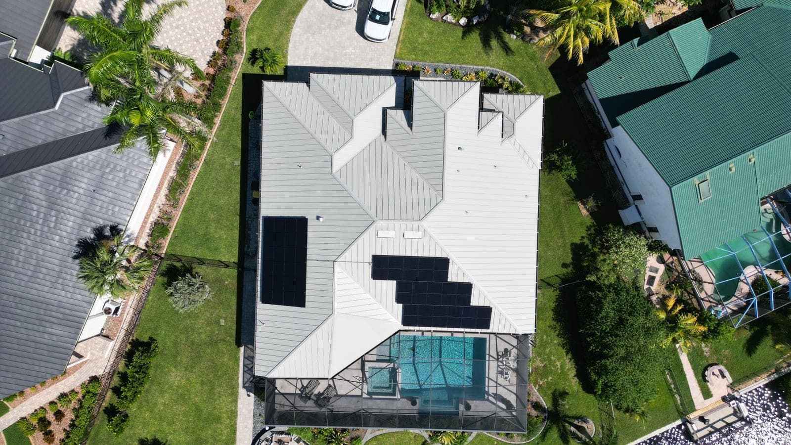 Aerial drone view of solar panels on modern metal roof home with pool in Southwest FL